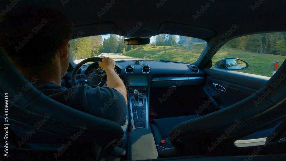 Young male driver driving through bends on a serpentine road over mountain pass