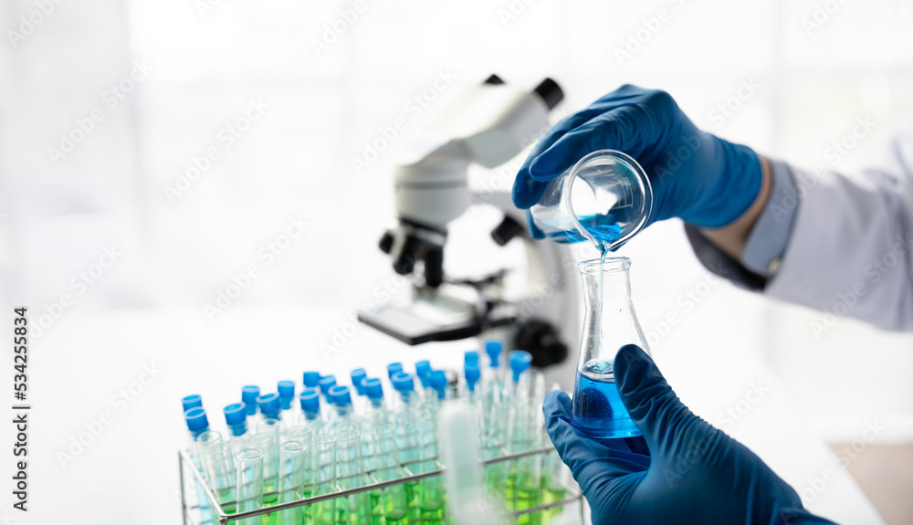 科学家在实验室工作，医生在实验室里看着透明溶液的试管