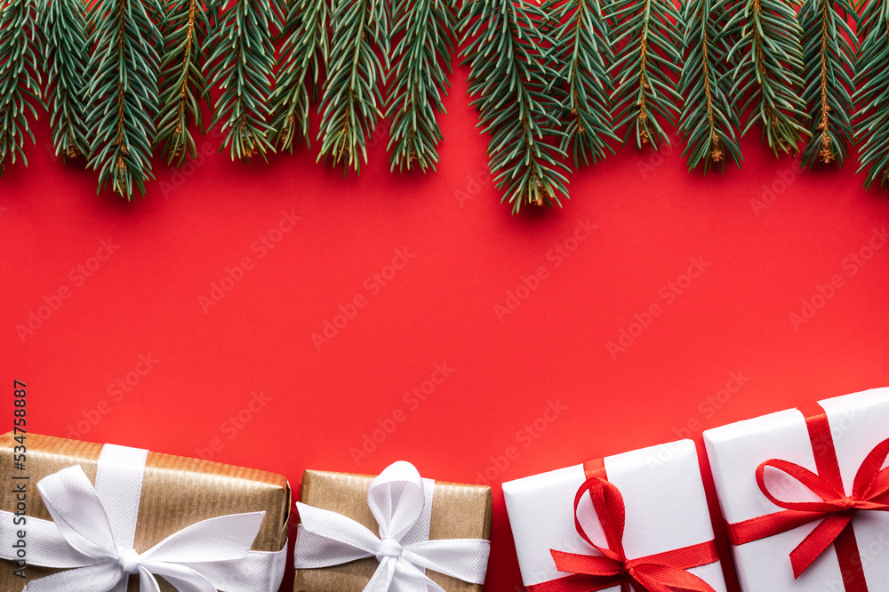 富有创意的圣诞背景，红色背景上有圣诞礼盒和松枝。平躺，