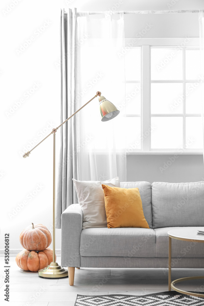 客厅的秋季内部，配有灰色沙发、灯和南瓜