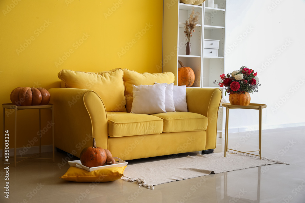 亮黄色客厅内部，配有沙发、南瓜和鲜花