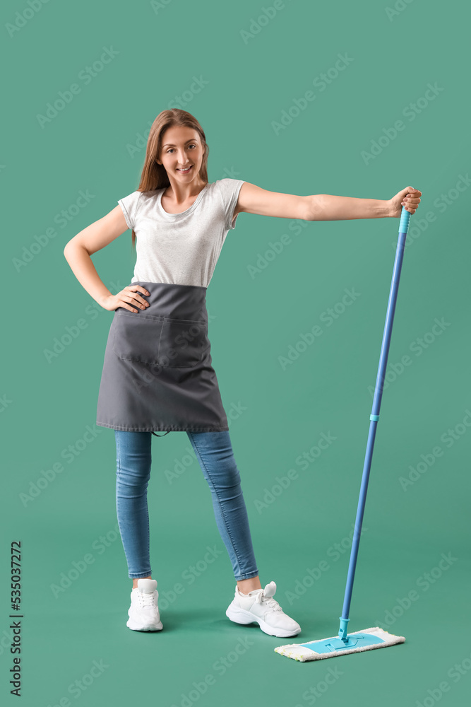 Young woman with mop on green background