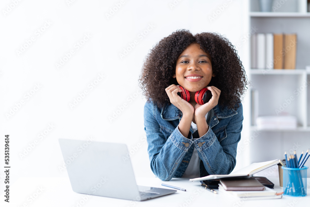 专注于在客厅里用笔记本电脑工作的年轻非洲女大学生。