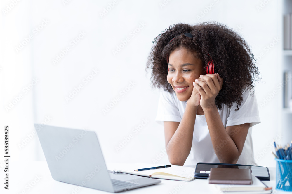 专注于在客厅里用笔记本电脑工作的年轻非洲女大学生。