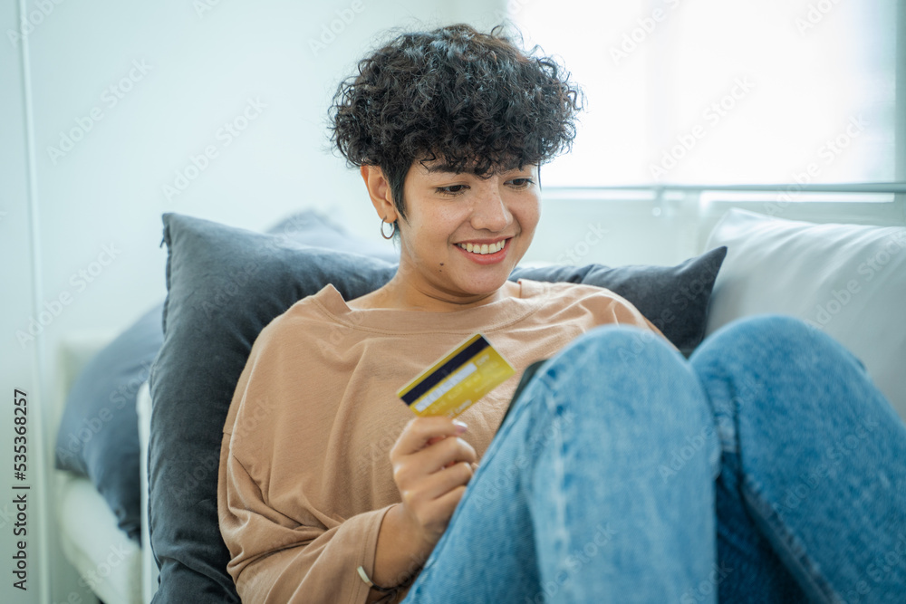 快乐的女人在客厅使用信用卡在线购物，出示信用卡。