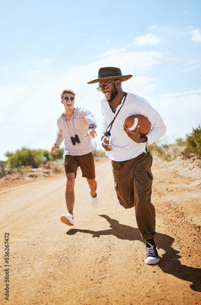 Football, friends and playing a game with man friends running on a dirt road or the dessert out in n