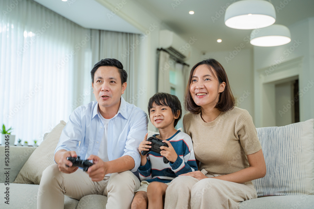 Family sitting on the couch together playing video games,Joyful family enjoying spending weekend fre