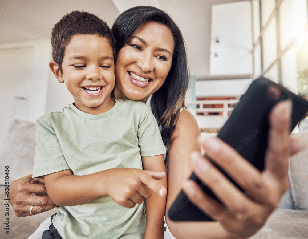 带着智能手机坐在沙发上玩游戏应用程序、有趣的社交媒体帖子或电子学习的快乐母子