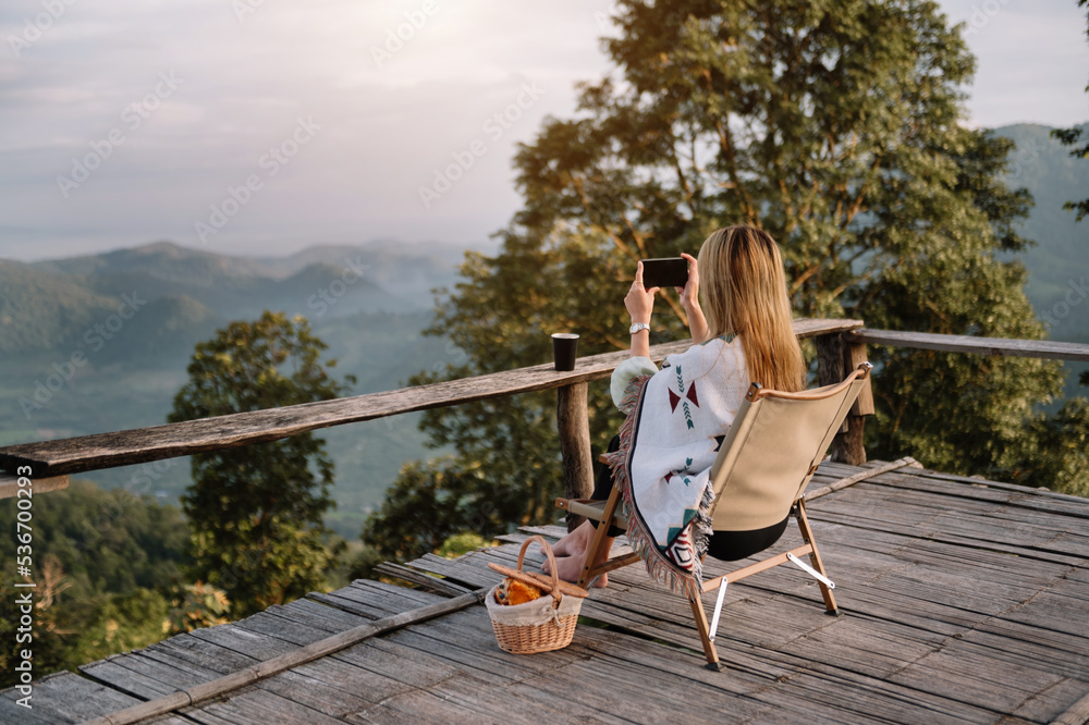 一位女性旅行者坐在那里眺望美丽的山脉、天空和自然的后视图像