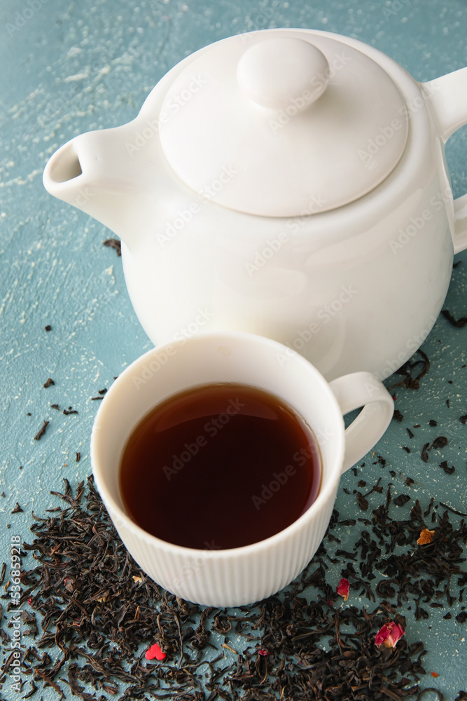 一杯红茶、茶壶和彩色背景的干叶，特写