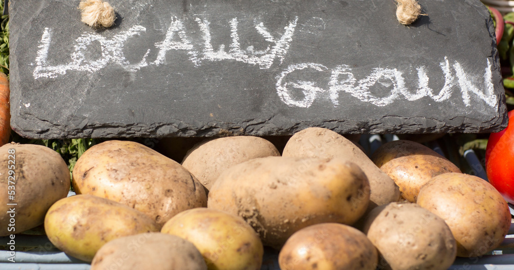 当地种植的石头上的文字与市场摊位上出售的生土豆的特写