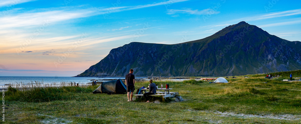 Junges Pärchen zeltet mit ihrem Zelt am Strand auf den Lofoten in Norwegen mit dem Meer und Bergen i