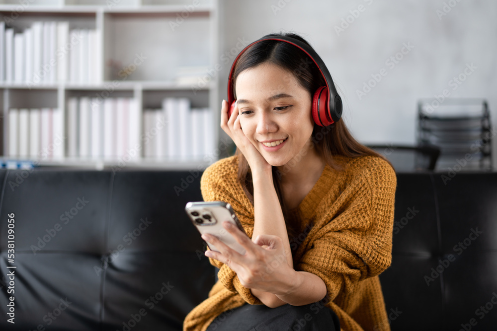 一位快乐的年轻亚洲女性用音乐应用程序的无线耳机听音乐的肖像