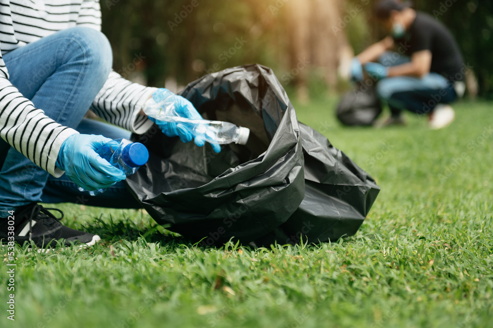 妇女用手将塑料垃圾收集到公园的回收袋中进行清洁。清理，
