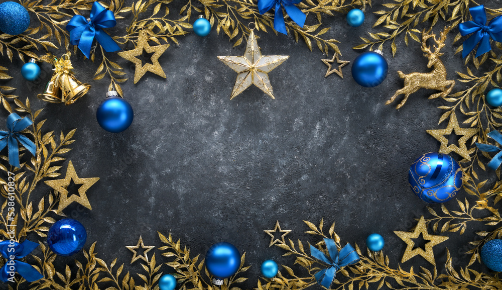 Christmas background with elegant gold adornments as a frame, blue baubles and bows, on a dark gray 