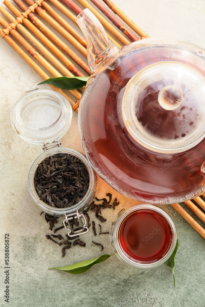 一杯红茶、一个茶壶和一个罐子，背景是干树叶，特写镜头