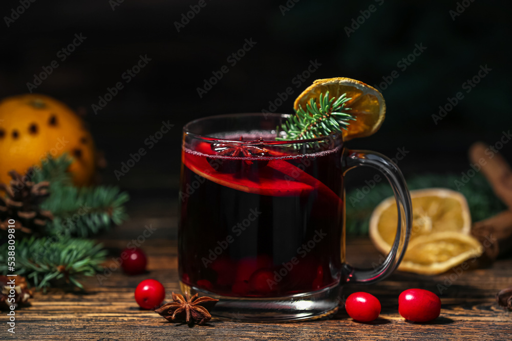 Glass cup of aromatic mulled wine on dark wooden table