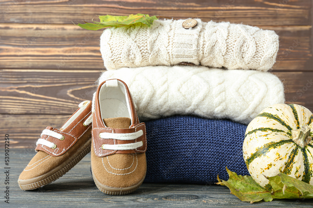 木制背景下的儿童毛衣、鞋子和秋季装饰