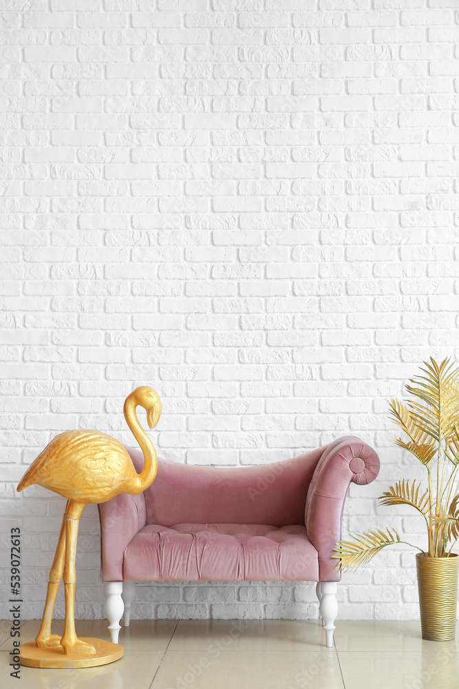 金色火烈鸟，舒适的沙发和白色砖墙附近的棕榈叶花瓶