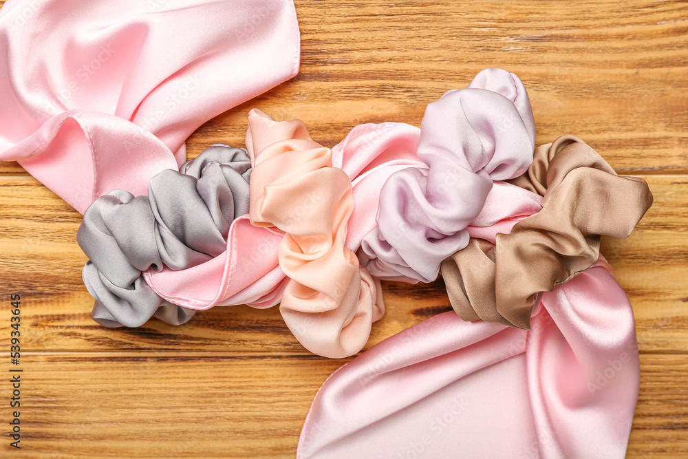 Silk scarf with different scrunchies on wooden background, closeup