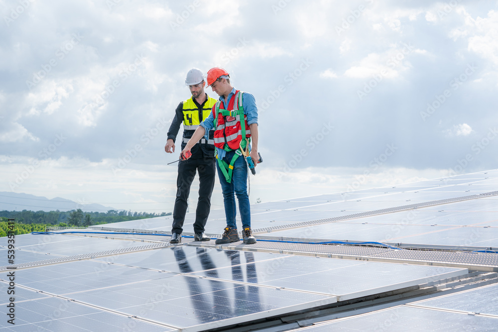 工程师或工人在仓库工厂的屋顶上安装太阳能电池，环保技术当选