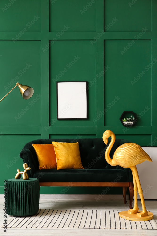 房间里靠近绿色墙壁的金色火烈鸟、沙发和空白相框