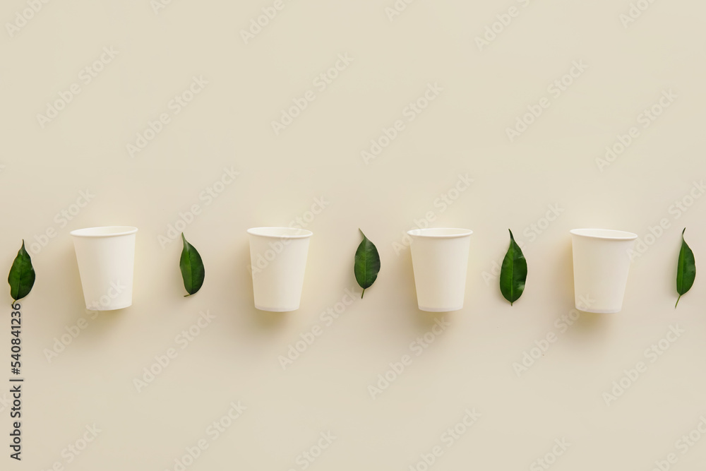 白色背景上的一排纸杯和植物叶子
