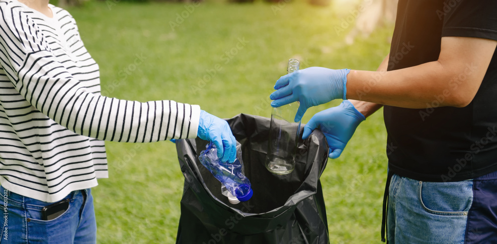 妇女用手将塑料垃圾收集到公园的回收袋中进行清洁。清理，