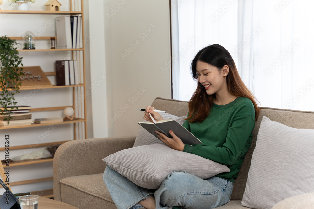 乐观的漂亮女孩穿着绿色衬衫在家用笔记本电脑工作的照片。