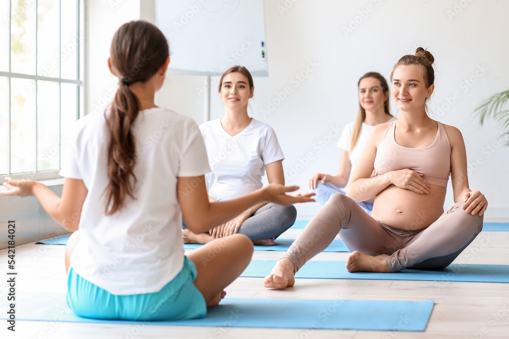 年轻孕妇在健身房和教练一起做瑜伽