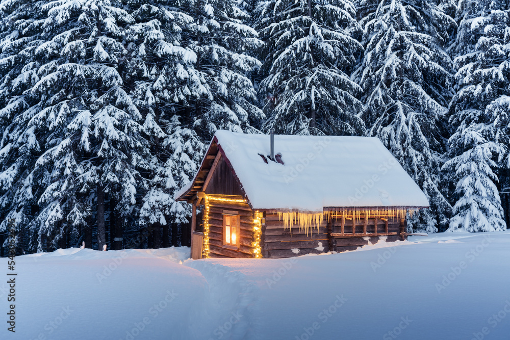 迷人的冬季景观，雪林中有发光的木屋。喀尔巴阡山脉的舒适小屋