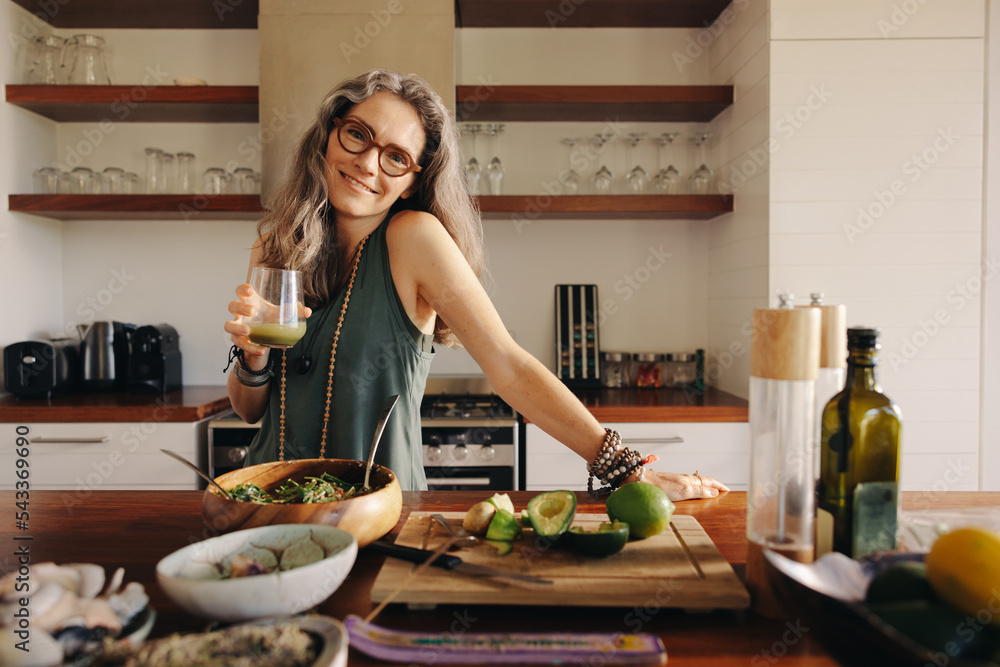 素食主义妇女在厨房里拿着一杯绿色果汁