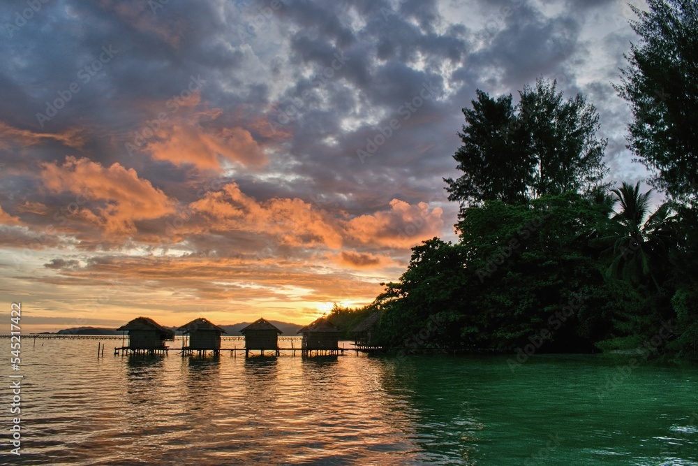 美丽的日落在海滩上典型的水上平房上方——西巴布亚拉贾安帕特的怀吉岛，
