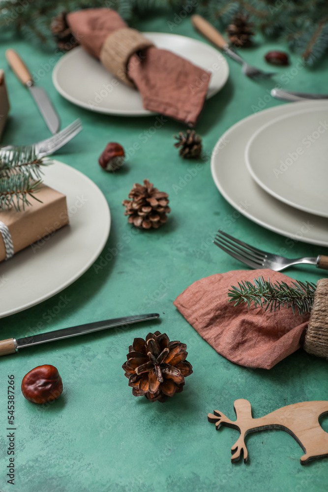 美丽的餐桌布置，绿色背景上有圣诞树枝和冷杉锥，特写