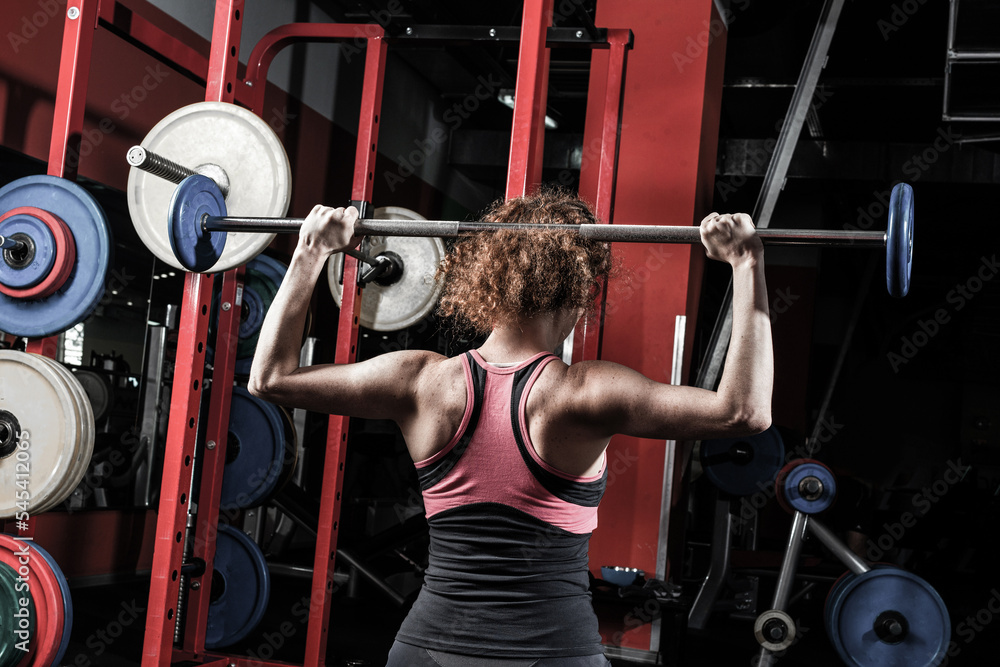 女健美运动员在健身房用杠铃健身