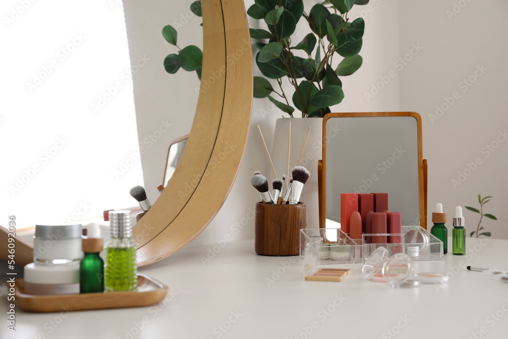 房间桌子上的不同化妆配件、化妆品和镜子