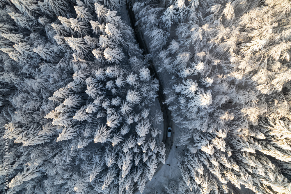 空中俯视：汽车在通往雪地森林的山路上行驶