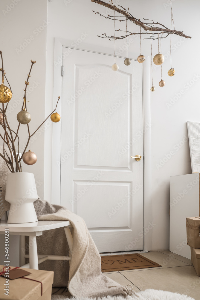 房间白色门附近挂着圣诞球的树枝