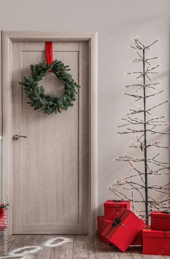 客厅里有带圣诞花环、发光灯和礼物的木门