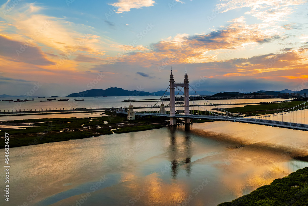 中国浙江舟山日落时分美丽的桥梁和河流自然风光鸟瞰图。