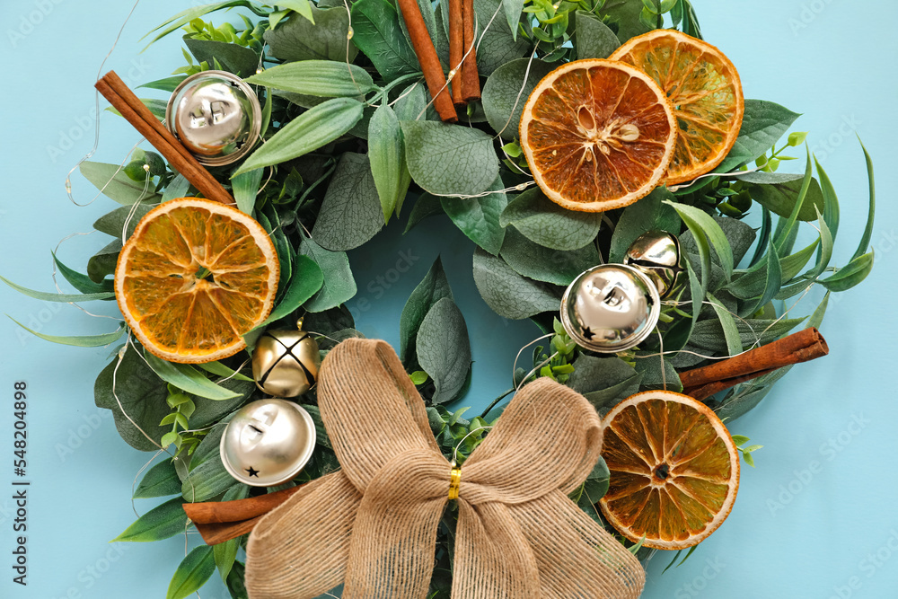美丽的圣诞花环，装饰有铃铛、橙色切片和肉桂色背景，clo