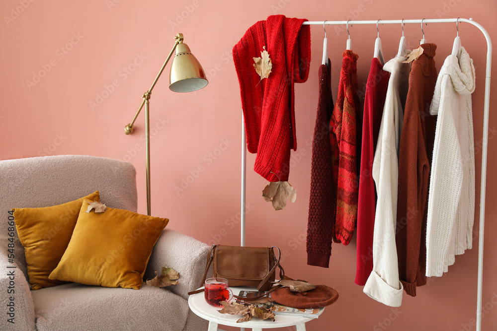 Rack with warm sweaters in interior of stylish room