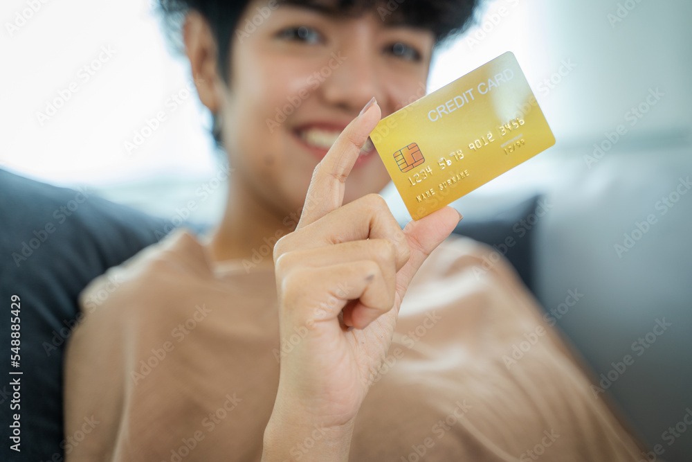 快乐女人在客厅用信用卡网购，出示信用卡。