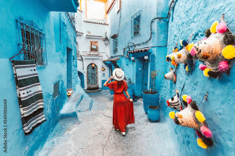身穿红色连衣裙的年轻女子参观摩洛哥的蓝色城市Chefchaouen-快乐的游客漫步在莫