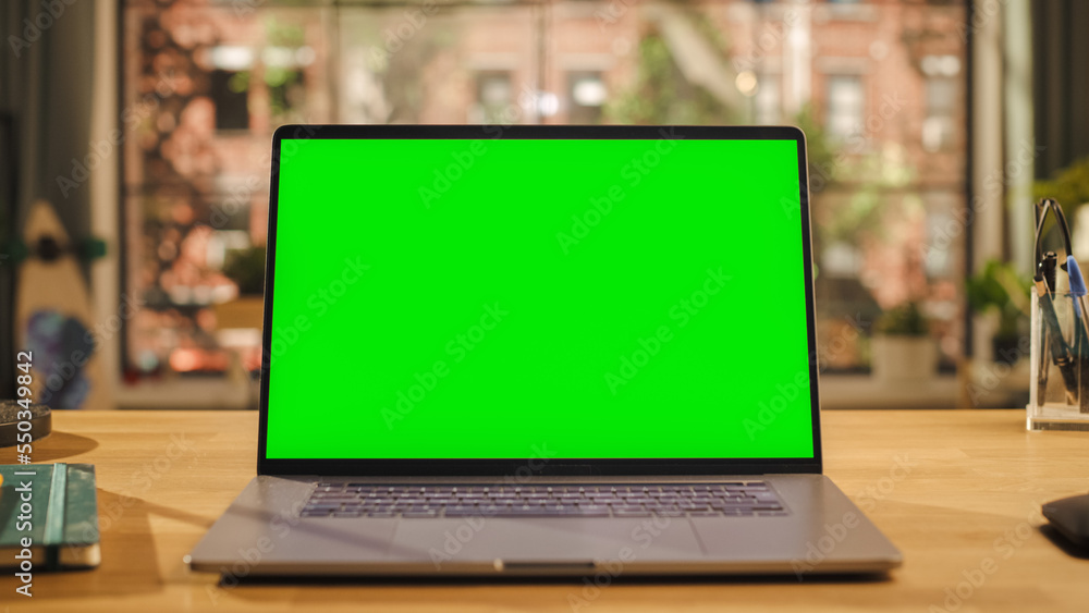 客厅木制桌子上的笔记本电脑显示屏，带实体绿屏。Chroma K