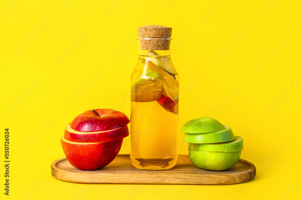 黄色背景上有一瓶苹果醋和水果的木板