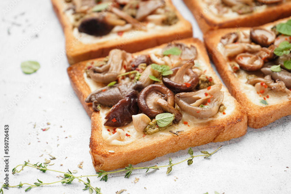 Delicious toasts with cream cheese, mushrooms and pesto sauce on light background, closeup