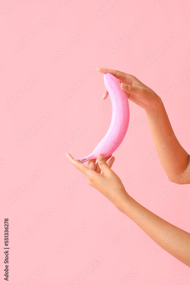 背景为粉红色香蕉的女性手