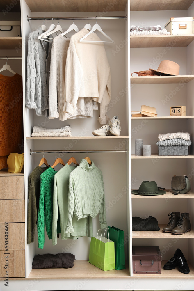 Hanging sweaters and shelves with accessories in wardrobe