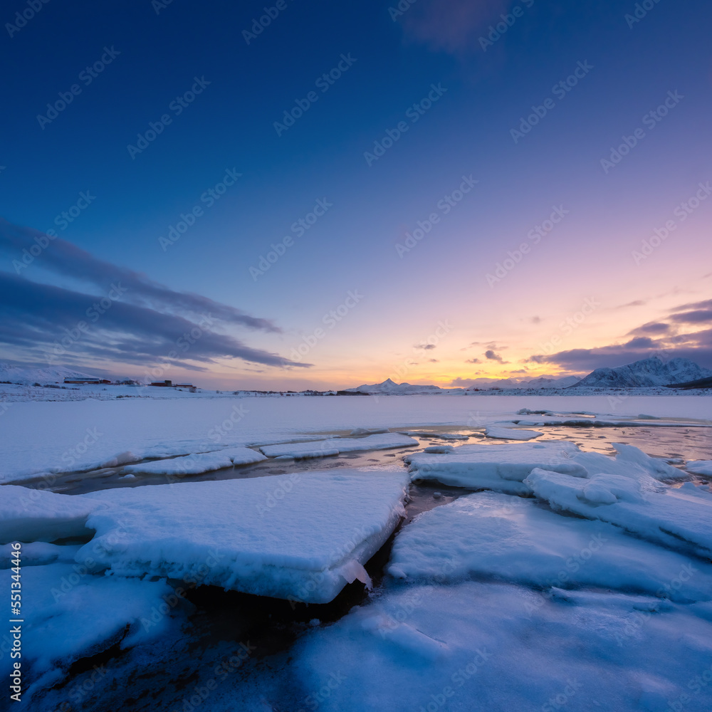 North, Norway. Winter landscape during sunset. Bright sky. Ice and snow on the shore. Reflections on